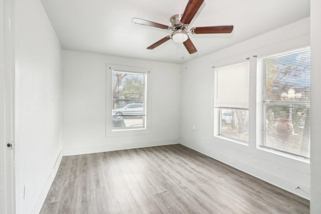 empty room featuring light wood finished floors, baseboards, and a ceiling fan