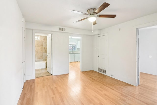 spare room featuring a ceiling fan, visible vents, a sink, and light wood finished floors