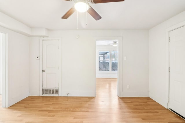 spare room featuring light wood-style flooring, visible vents, and baseboards