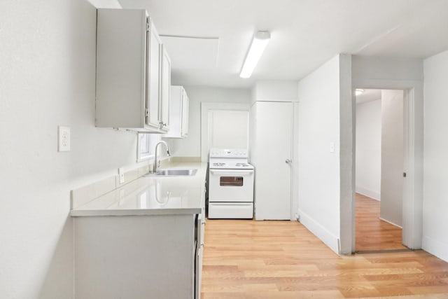 kitchen with electric stove, light countertops, light wood-style flooring, a sink, and baseboards