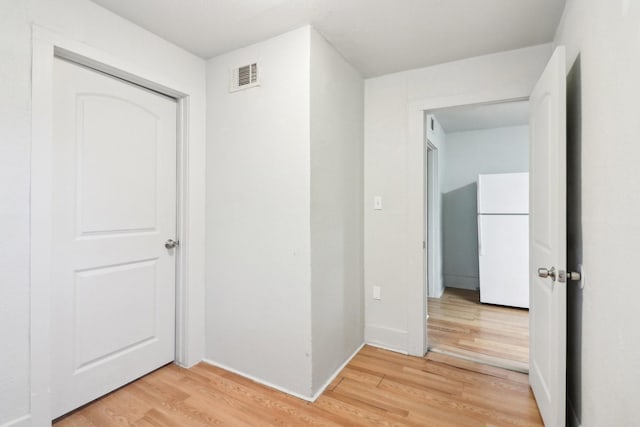 hall featuring visible vents, baseboards, and wood finished floors