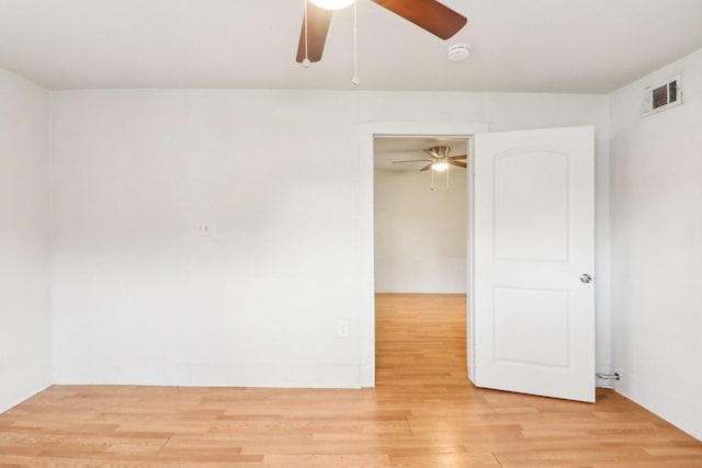 empty room with ceiling fan, visible vents, and wood finished floors