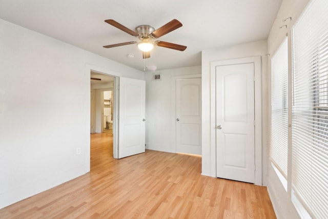 unfurnished bedroom featuring baseboards, a ceiling fan, visible vents, and light wood-style floors