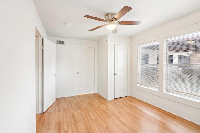 spare room featuring light wood-type flooring, visible vents, and ceiling fan