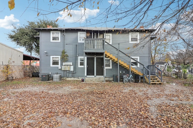 rear view of property with central air condition unit, a chimney, stairs, and fence