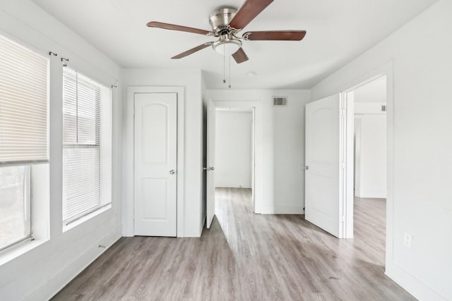 unfurnished bedroom featuring light wood-style floors, visible vents, ceiling fan, and baseboards