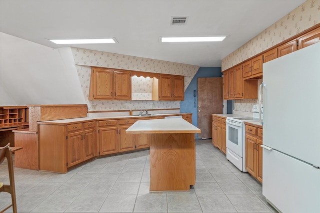 kitchen featuring light tile patterned floors, white appliances, a kitchen island, and sink