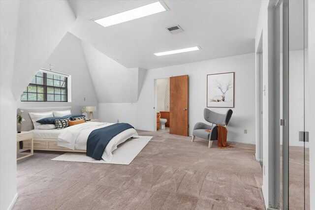 carpeted bedroom featuring vaulted ceiling and ensuite bath