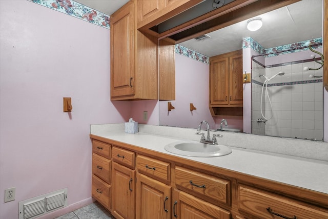 bathroom featuring tiled shower, vanity, and tile patterned floors