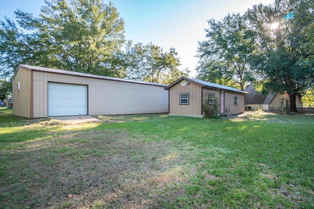 rear view of property with a lawn, an outdoor structure, and a garage