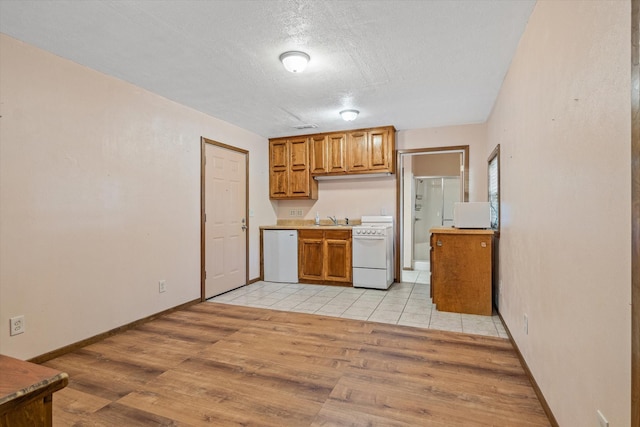 kitchen with a textured ceiling, sink, light hardwood / wood-style floors, and white appliances