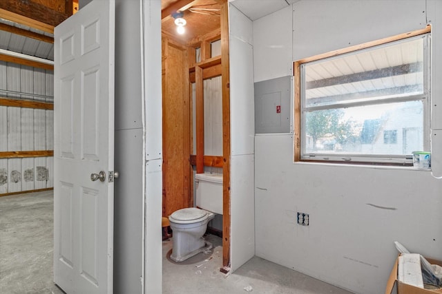 bathroom featuring electric panel, concrete floors, and toilet