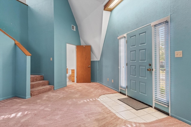 carpeted foyer featuring high vaulted ceiling