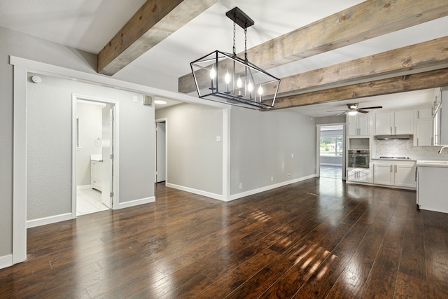 unfurnished living room featuring beamed ceiling, ceiling fan with notable chandelier, dark hardwood / wood-style floors, and sink