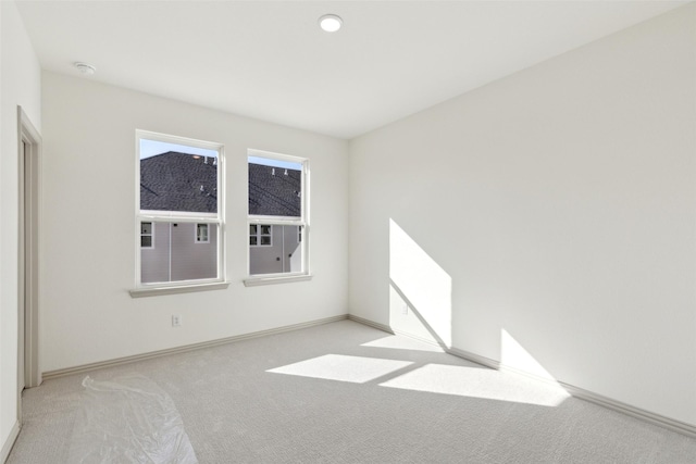 unfurnished room with light carpet and baseboards