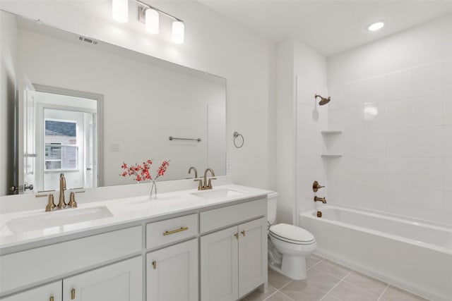 full bathroom with toilet, double vanity, a sink, and tile patterned floors