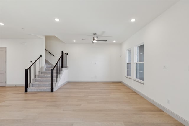 empty room featuring light wood-type flooring, stairway, and recessed lighting