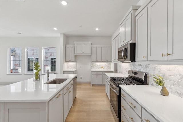 kitchen featuring a center island with sink, recessed lighting, light countertops, appliances with stainless steel finishes, and a sink