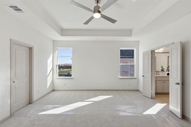 bedroom featuring visible vents, a tray ceiling, and light colored carpet