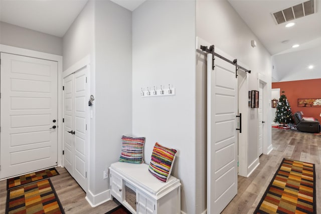 hallway with light wood-type flooring and a barn door