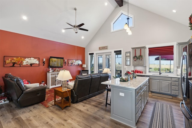 kitchen with gray cabinetry, a center island, high vaulted ceiling, and wood-type flooring