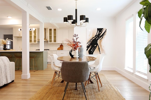 dining room featuring crown molding, light hardwood / wood-style flooring, and a chandelier