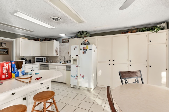 kitchen with sink, stainless steel appliances, white cabinets, light tile patterned flooring, and decorative backsplash