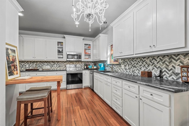 kitchen with white cabinetry, sink, light hardwood / wood-style flooring, pendant lighting, and appliances with stainless steel finishes