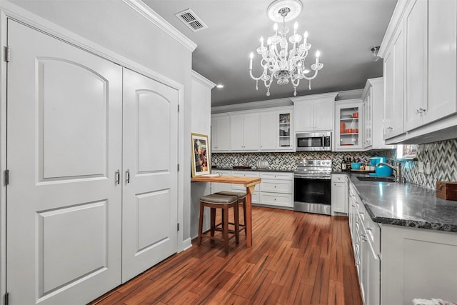 kitchen with white cabinets, appliances with stainless steel finishes, dark hardwood / wood-style flooring, and sink