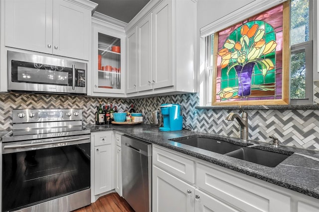 kitchen with white cabinetry, sink, backsplash, dark stone countertops, and appliances with stainless steel finishes