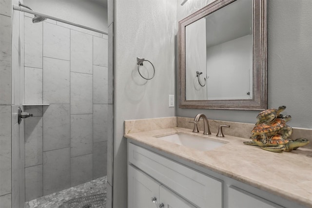 bathroom featuring a tile shower and vanity