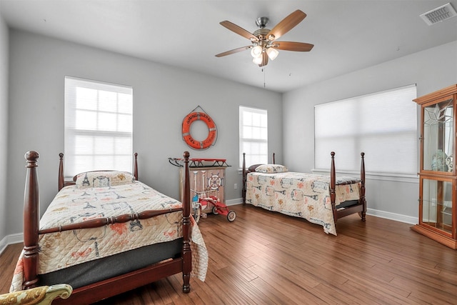 bedroom featuring dark wood-style floors, visible vents, ceiling fan, and baseboards