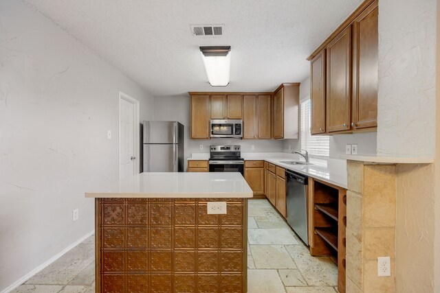 kitchen featuring stainless steel appliances, a kitchen island, sink, and a textured ceiling