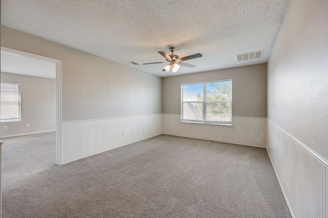 carpeted spare room with ceiling fan and a textured ceiling