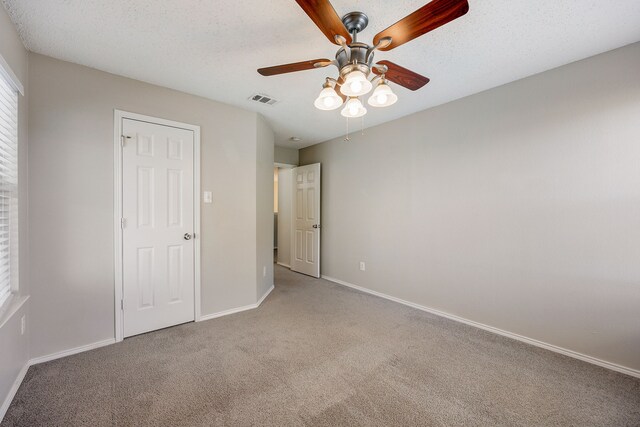 unfurnished bedroom with ceiling fan, light colored carpet, and a textured ceiling