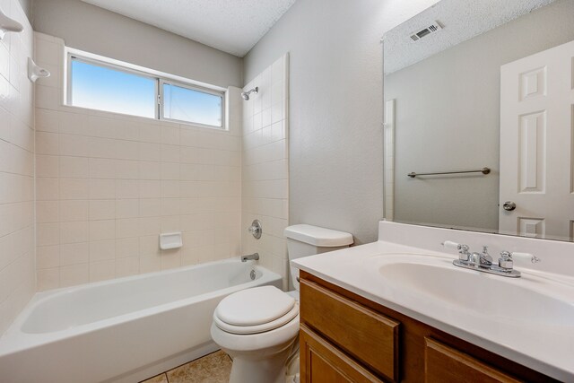 full bathroom with vanity, a textured ceiling, tile patterned floors, toilet, and tiled shower / bath