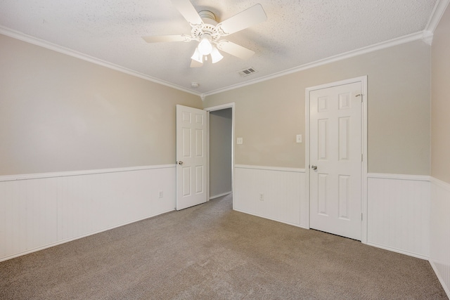 spare room featuring ceiling fan, ornamental molding, carpet, and a textured ceiling