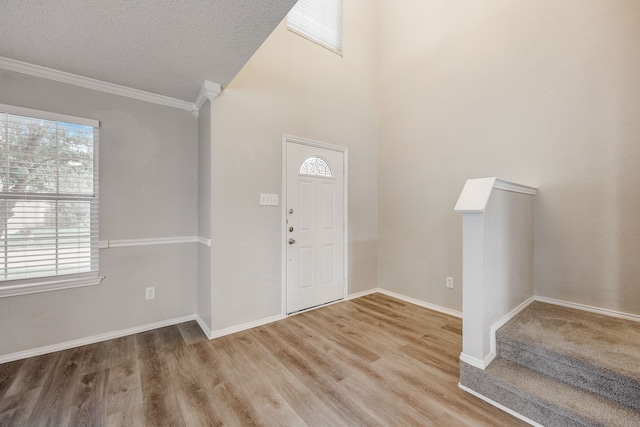 entrance foyer with crown molding, hardwood / wood-style flooring, and a textured ceiling