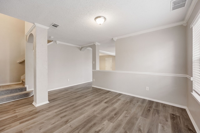 spare room with ornamental molding, wood-type flooring, and a textured ceiling