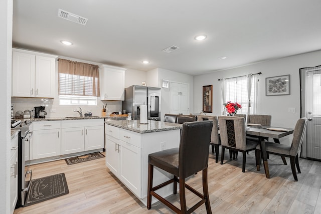 kitchen with white cabinetry, a center island, a healthy amount of sunlight, and appliances with stainless steel finishes