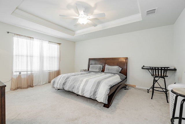 carpeted bedroom with ceiling fan, a raised ceiling, and crown molding