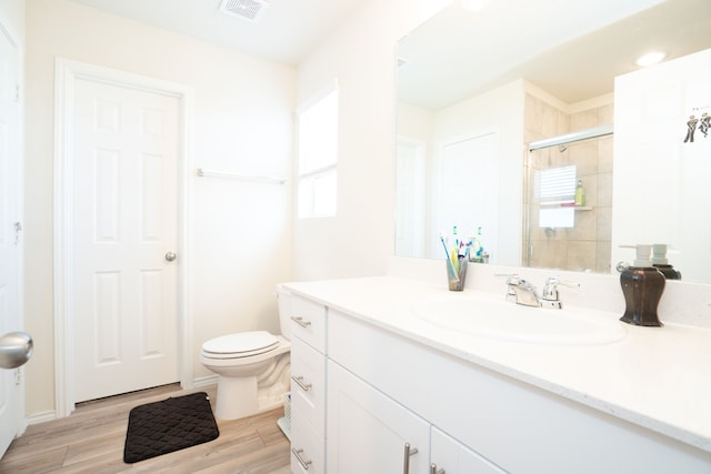 bathroom with vanity, wood-type flooring, a shower with shower door, and toilet