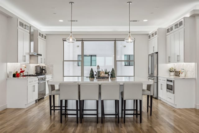 kitchen with white cabinetry, an island with sink, and high end appliances