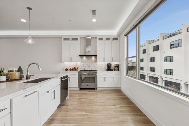 kitchen with white cabinetry, pendant lighting, wall chimney exhaust hood, and stainless steel appliances