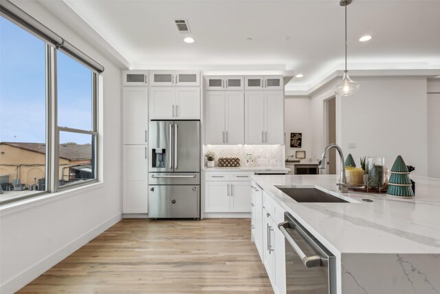 kitchen with white cabinets, sink, stainless steel appliances, and hanging light fixtures