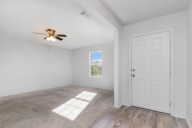 foyer entrance with ceiling fan and light colored carpet