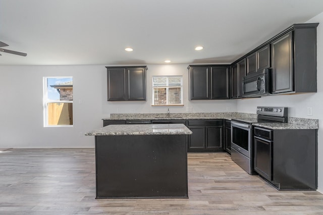 kitchen with stainless steel electric stove, sink, light hardwood / wood-style flooring, a kitchen island, and light stone counters