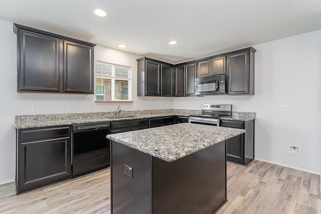 kitchen featuring light stone counters, sink, black appliances, a center island, and light hardwood / wood-style floors