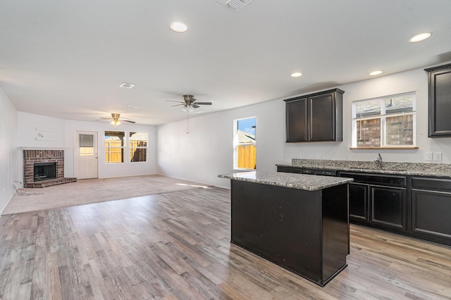 kitchen with light hardwood / wood-style flooring, a kitchen island, ceiling fan, and sink