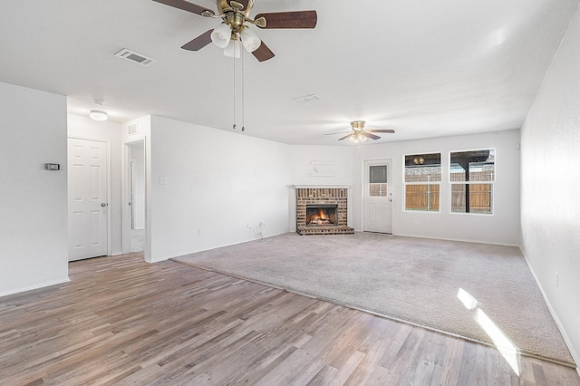 unfurnished living room featuring a fireplace, light hardwood / wood-style flooring, and ceiling fan